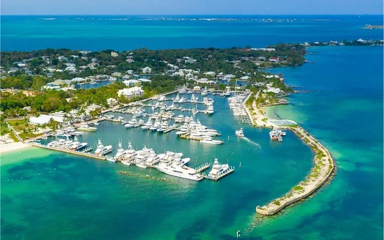 Aerial view of a marina full of boats behind a curved breakwater in Abaco, The Bahamas