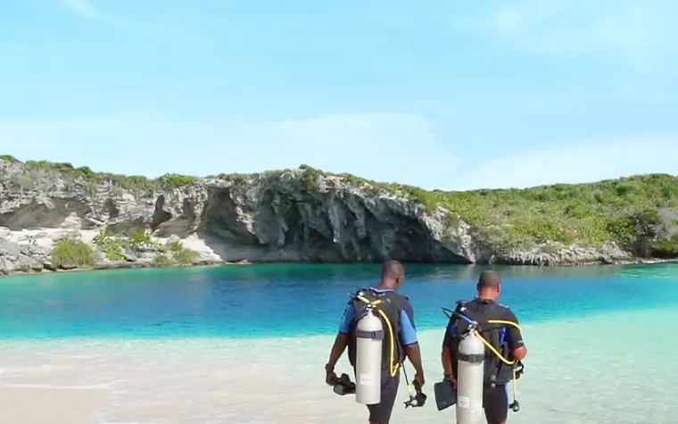 Two divers walking into the water at Dean's Blue Hole on Long Island, The Bahamas