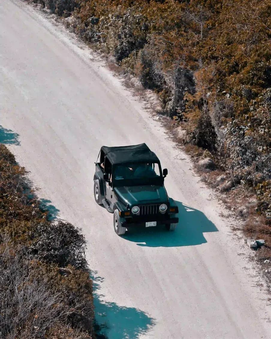 A vehicle on a quiet coastal road beside turquoise water in The Bahamas