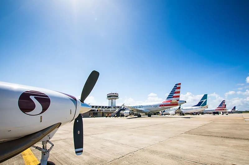 Aircraft parked on the tarmac in front of the control tower at Philip S. W. Goldson International Airport, Belize