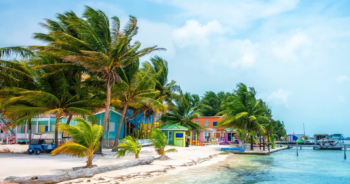 Colourful wooden cabanas and leaning palms along a white-sand beach on Caye Caulker