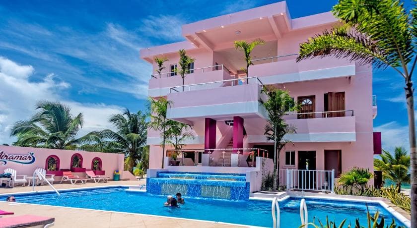 Pink beachfront hotel with a turquoise pool and palms on the Placencia peninsula