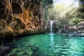 Annandale Falls cascading into a green pool surrounded by rainforest in central Grenada