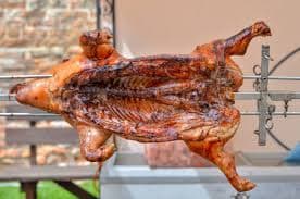 A whole pig spit-roasting over coals at a Guavate lechonera