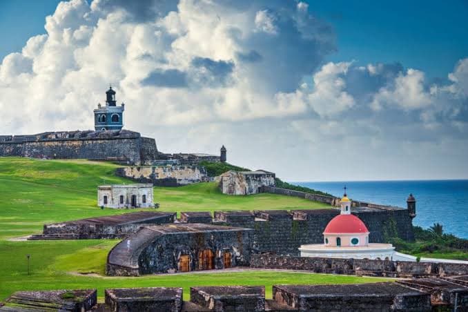 The stone ramparts of El Morro fortress on green headland above the sea in Old San Juan