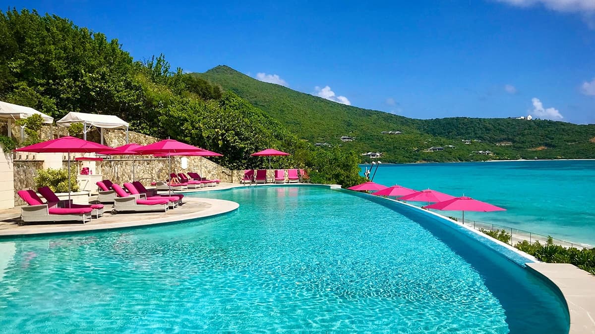 Infinity pool with pink sun loungers overlooking turquoise waters in the Grenadines