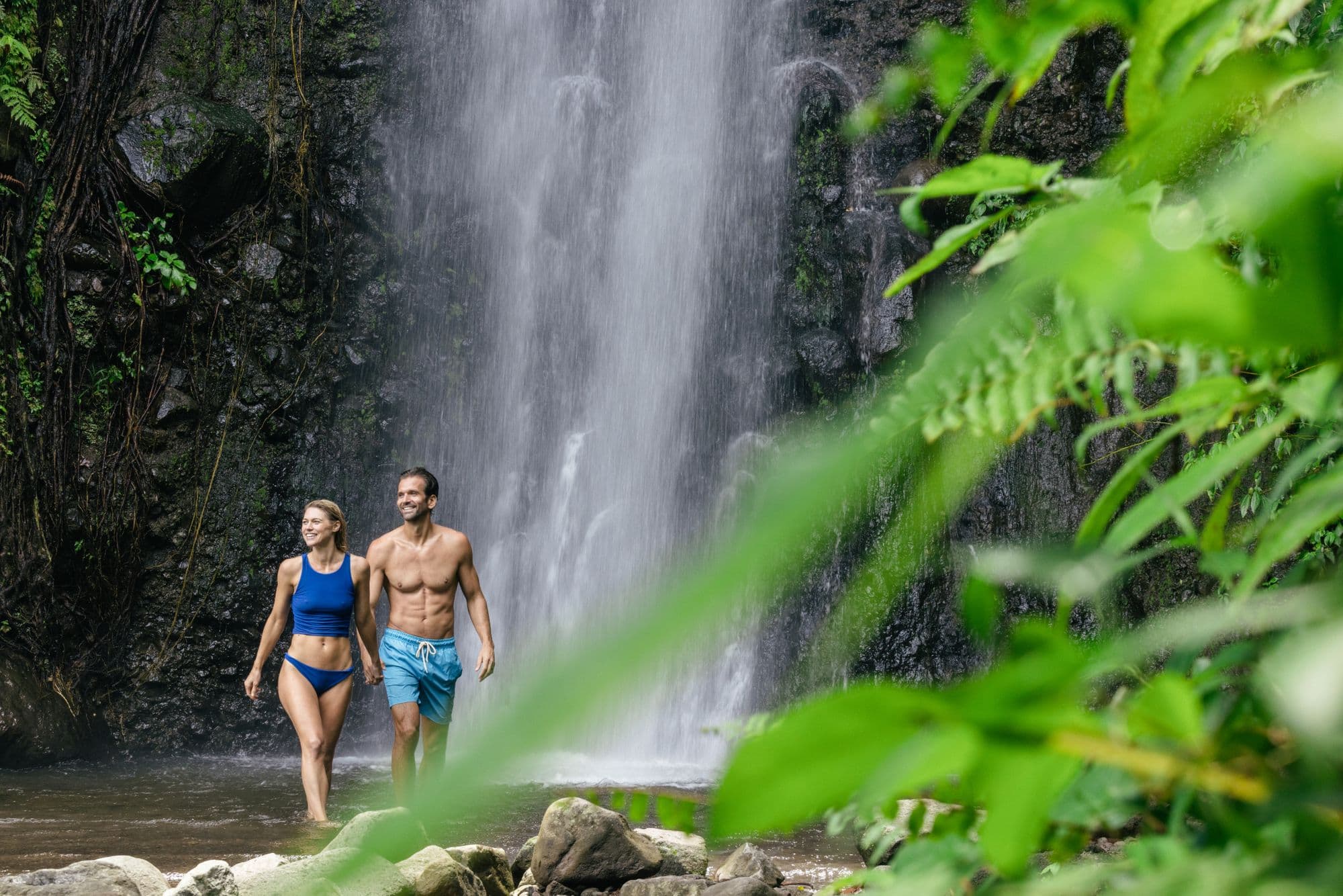 Couple walking out of a waterfall in the rainforest, Saint Vincent