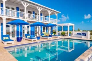 Poolside loungers and blue umbrellas at a two-storey villa near Chalk Sound