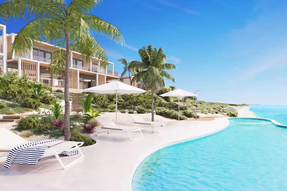 Infinity pool and sun loungers at a beachfront resort above the water at Long Bay