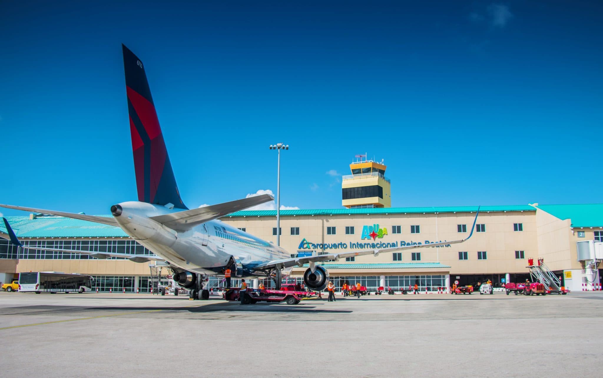 An aircraft on the apron in front of the terminal and control tower at Queen Beatrix International Airport, Aruba (AUA)