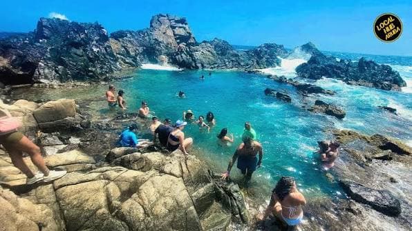 Swimmers in the Natural Pool (Conchi) ringed by volcanic rock, Aruba