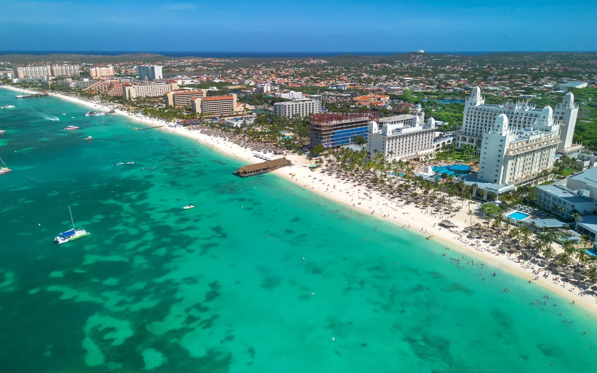 High-rise resorts, palapas and turquoise water along Palm Beach, Aruba