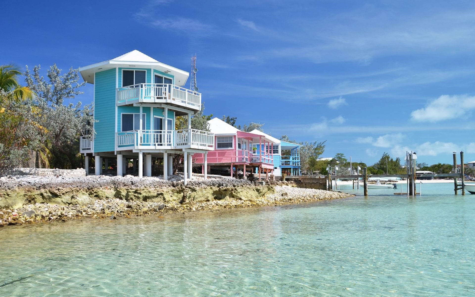 A small wooden pier stretching into extraordinarily clear shallow turquoise water at a boutique resort in Exuma, Bahamas
