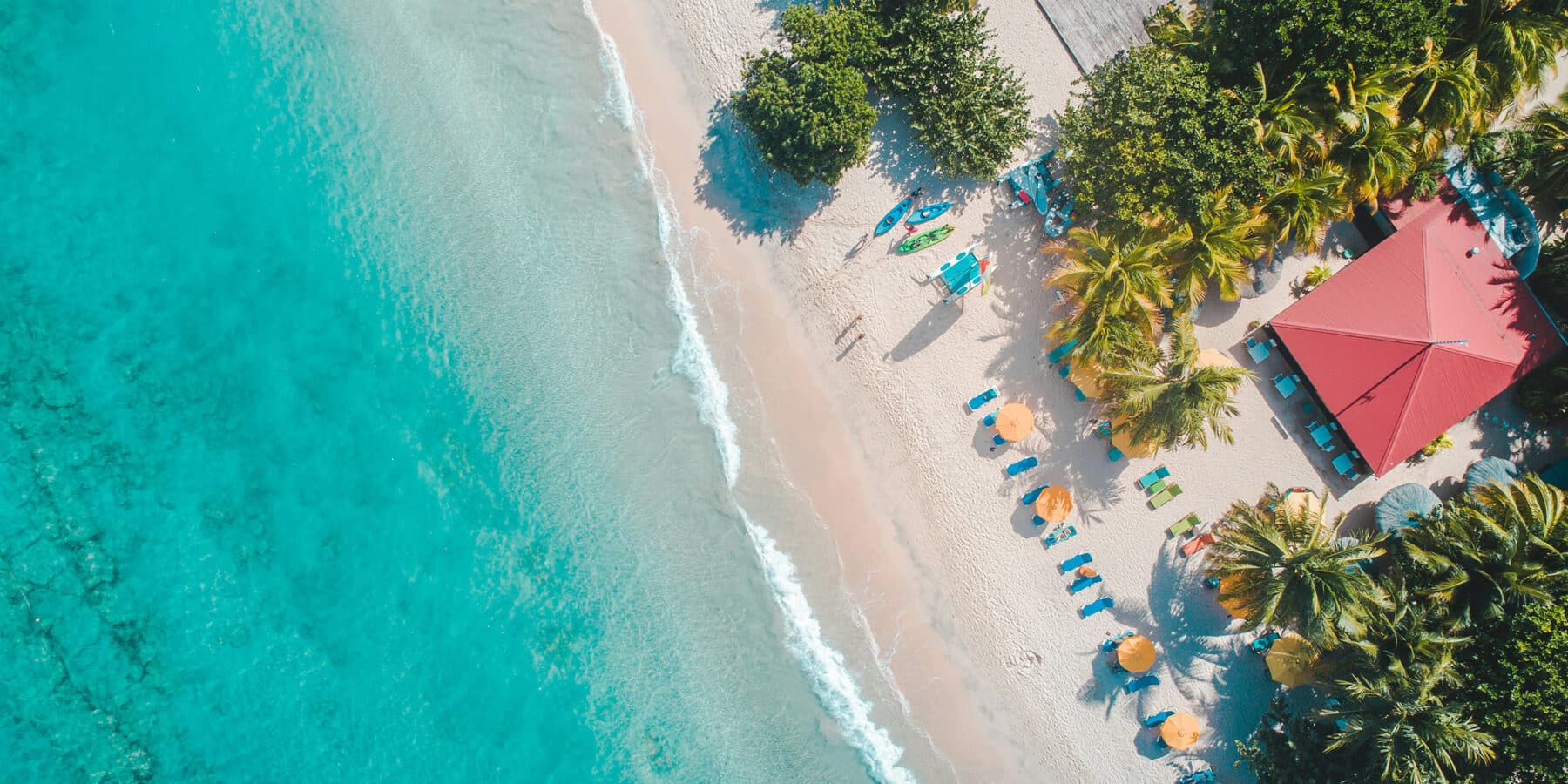 Aerial view of a palm fringed white sand beach and clear turquoise water on the Platinum Coast of Barbados