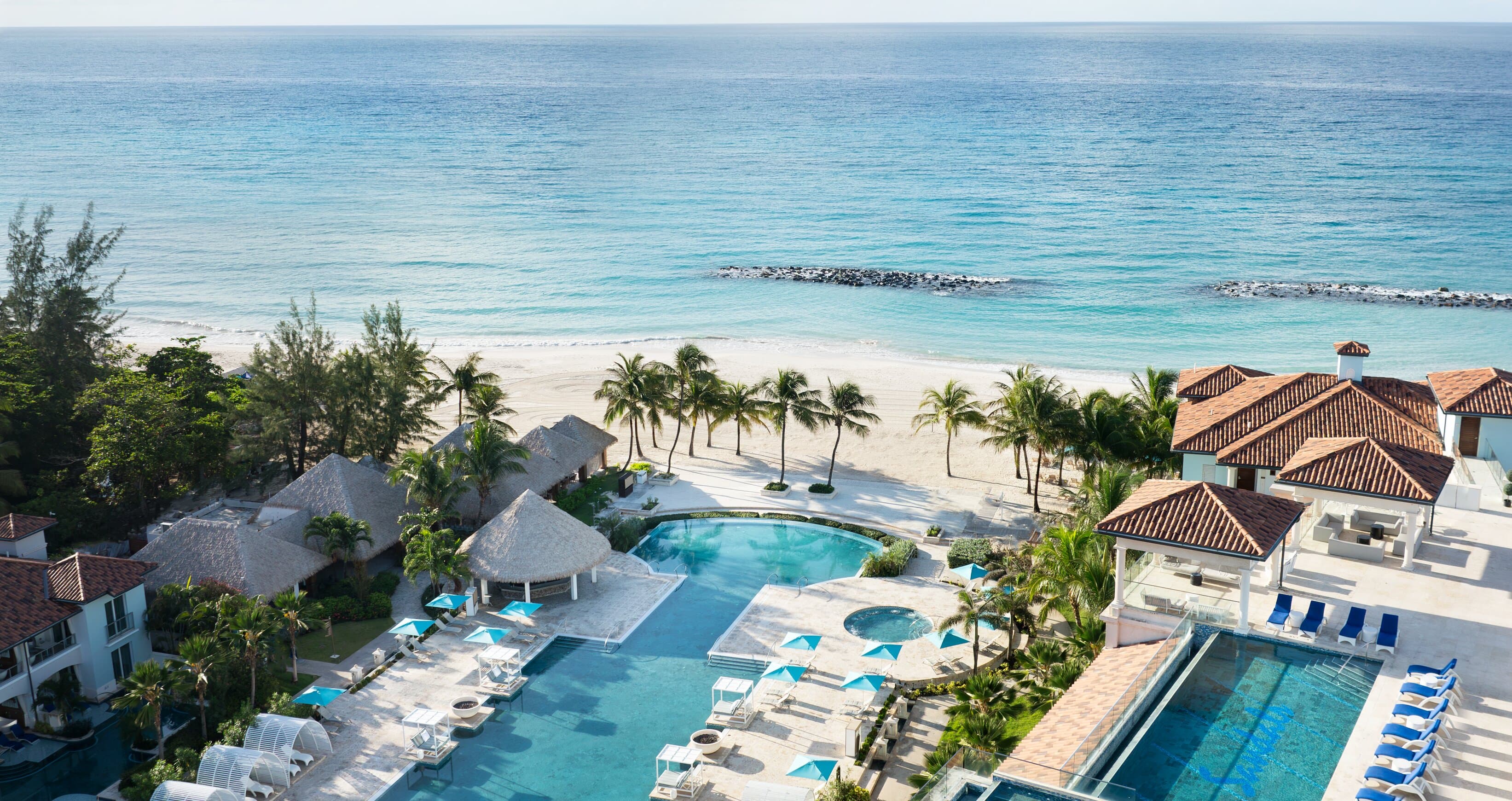 Aerial view of a beachfront resort with palm lined white sand beach, turquoise pools and the clear Caribbean Sea on the west coast of Barbados
