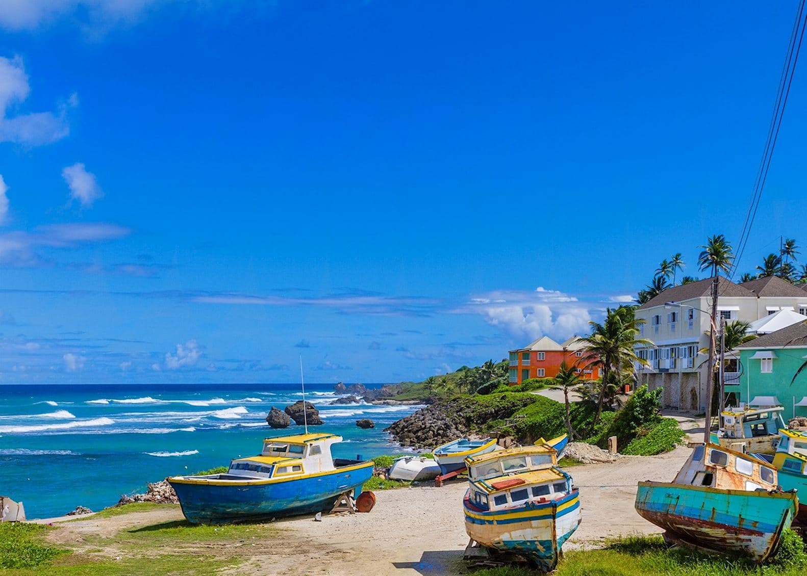 Colourful wooden fishing boats on the sand beside the rugged Atlantic surf at Bathsheba on the east coast of Barbados