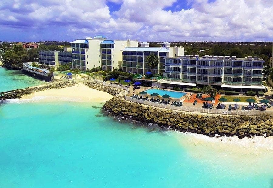 Aerial view of a beachfront hotel beside a sheltered turquoise cove on the south coast of Barbados