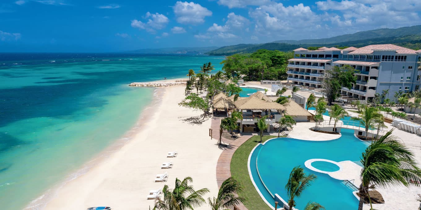 A beachfront resort with curved pools, palm thatch bars and turquoise sea near Ocho Rios, Jamaica