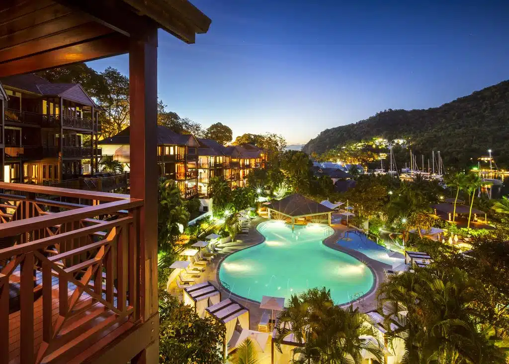 Resort pool and balconies lit up at dusk above the yacht-filled harbour of Marigot Bay, Saint Lucia