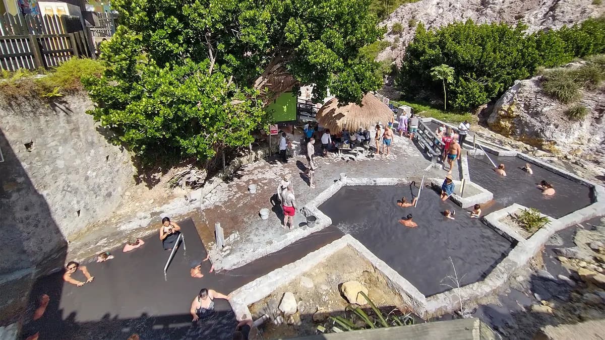 Visitors bathing in the warm grey geothermal mud pools at Sulphur Springs, the drive-in volcano near Soufrière, Saint Lucia