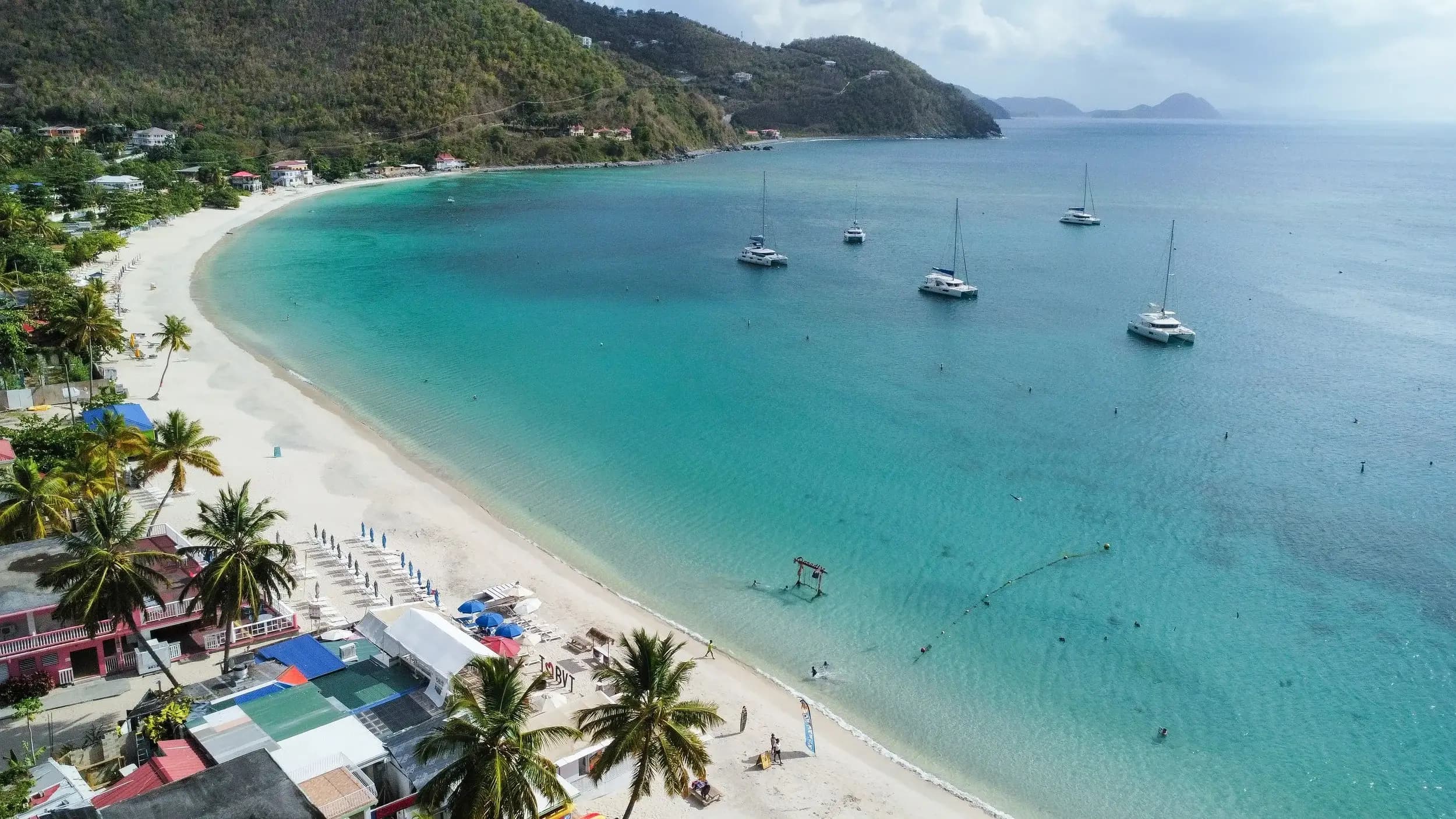 Palm-lined turquoise water at Cane Garden Bay, a short transfer from Beef Island Airport (EIS), Tortola